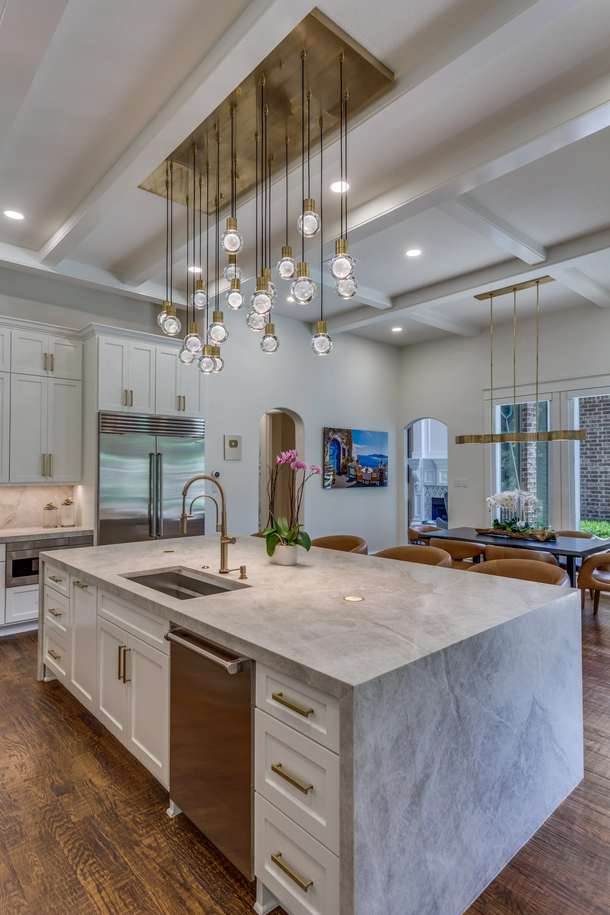 Waterfall-edge Taj Mahal quartzite island with mitered edge, brass fixtures, and dishwasher