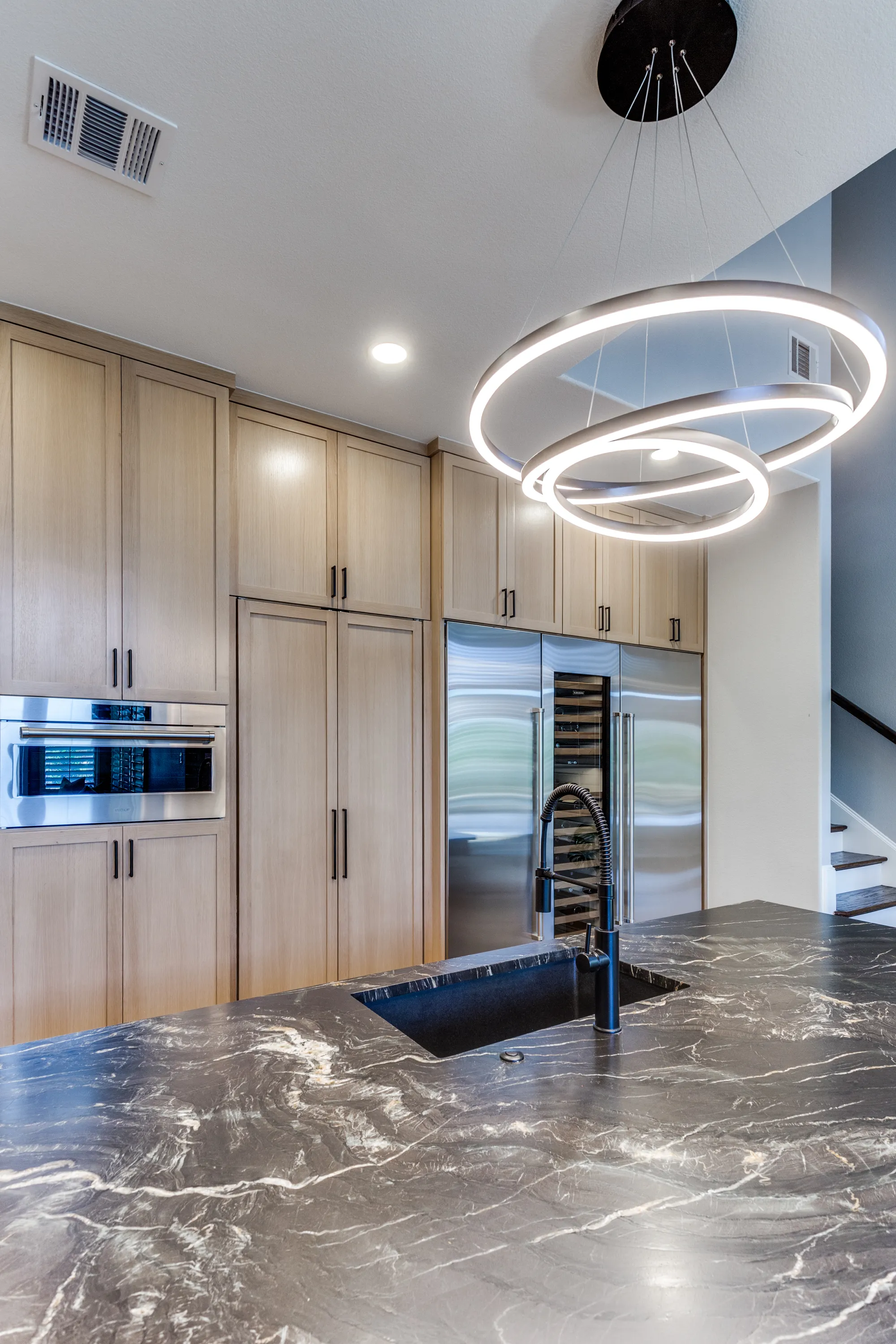 Belvedere leather granite island with matte black fixtures and built-in wine storage beyond