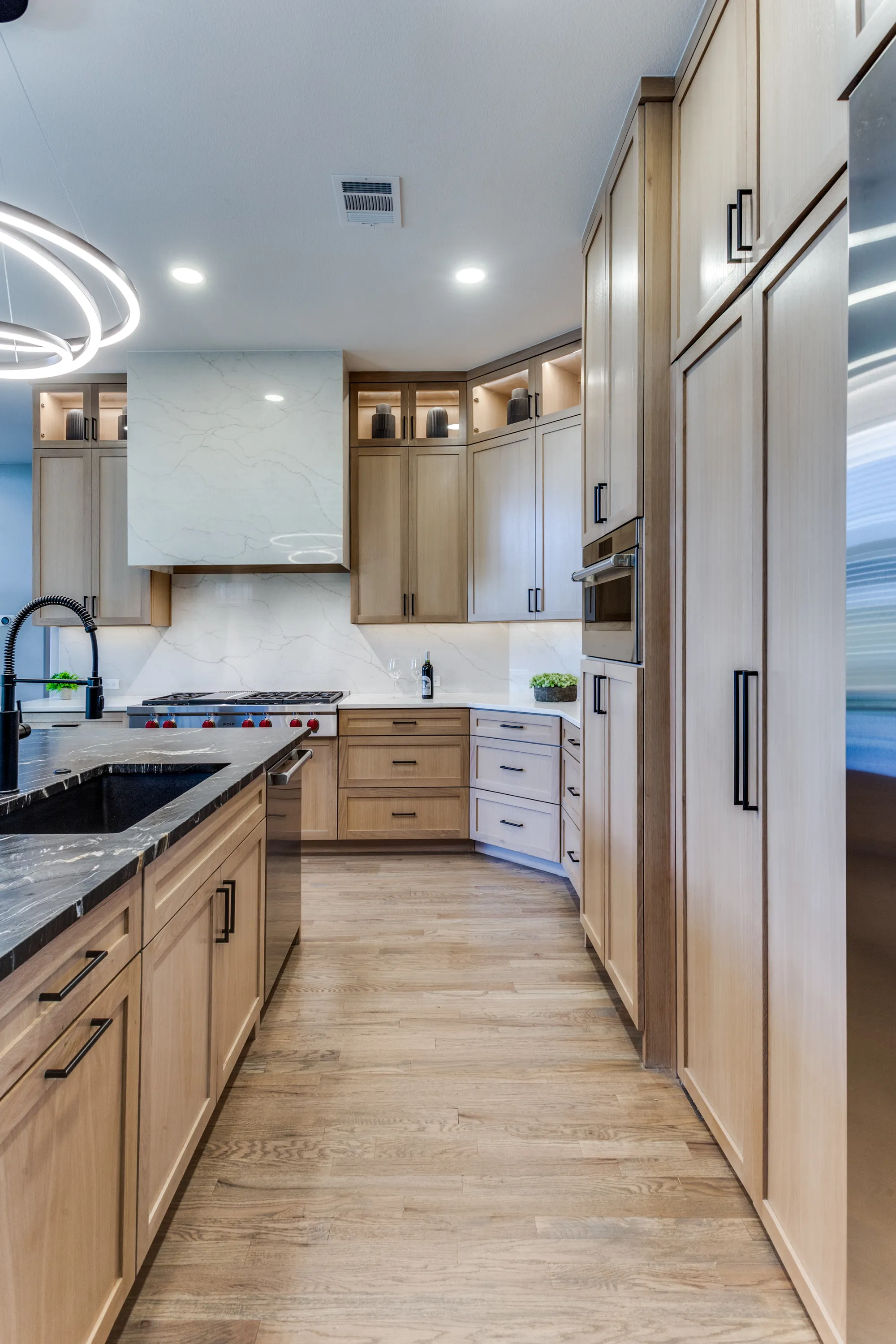 Wolf cooktop beneath a Calacatta quartz hood, flanked by illuminated display cabinetry