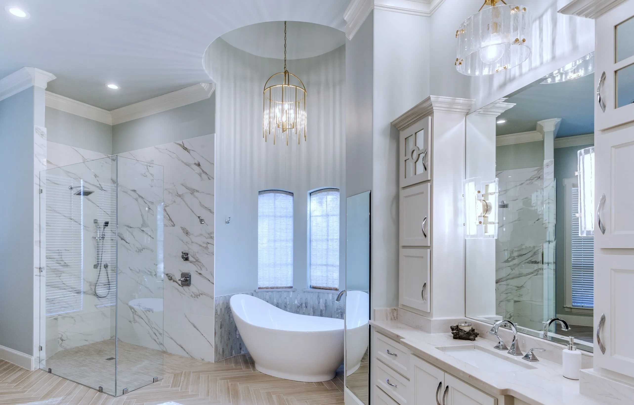 Wide view of the curbless walk-in marble shower, the domed tub alcove with arched windows, and the vanity, all in one frame