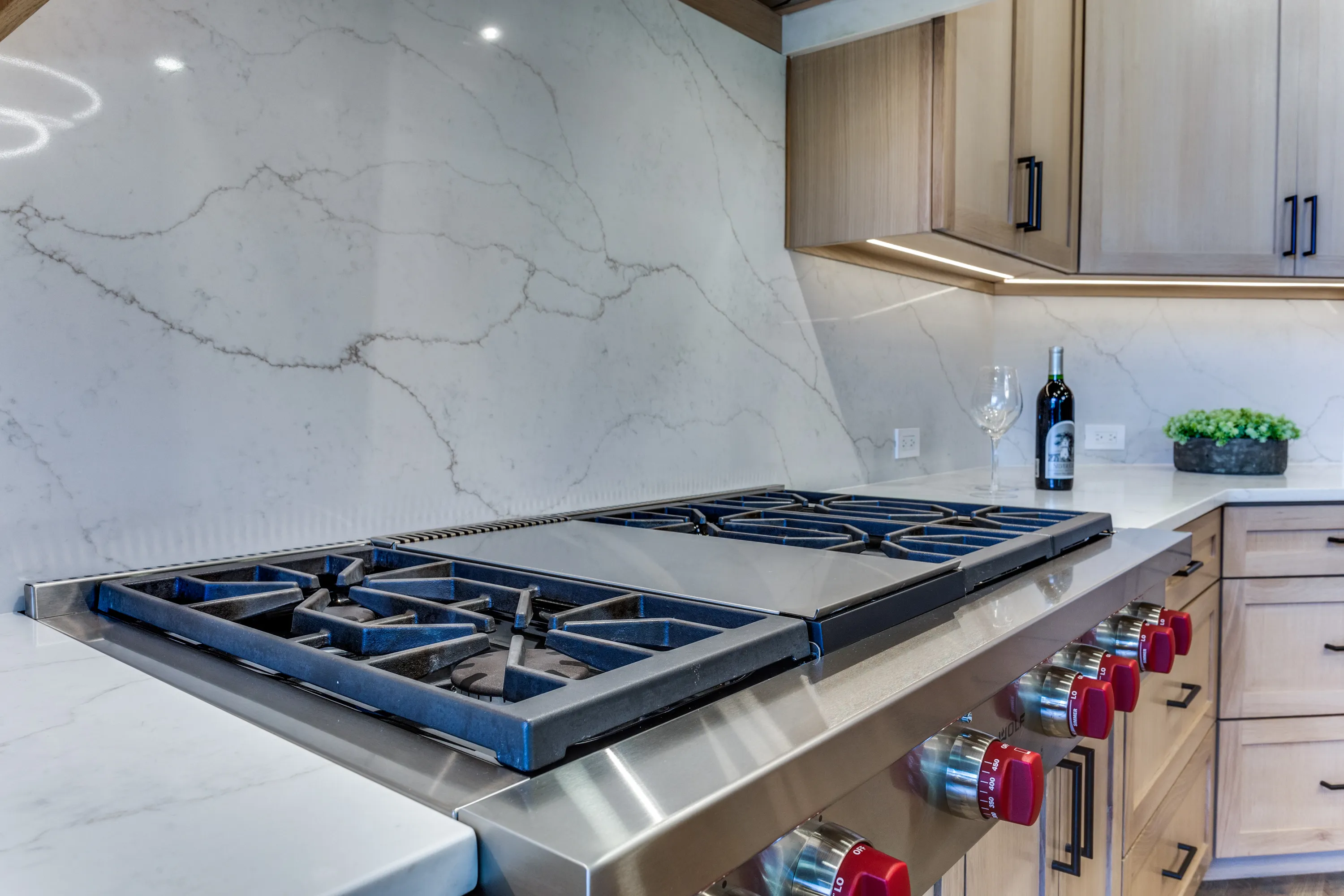 Wolf cooktop detail with under-cabinet lighting and Calacatta quartz backsplash