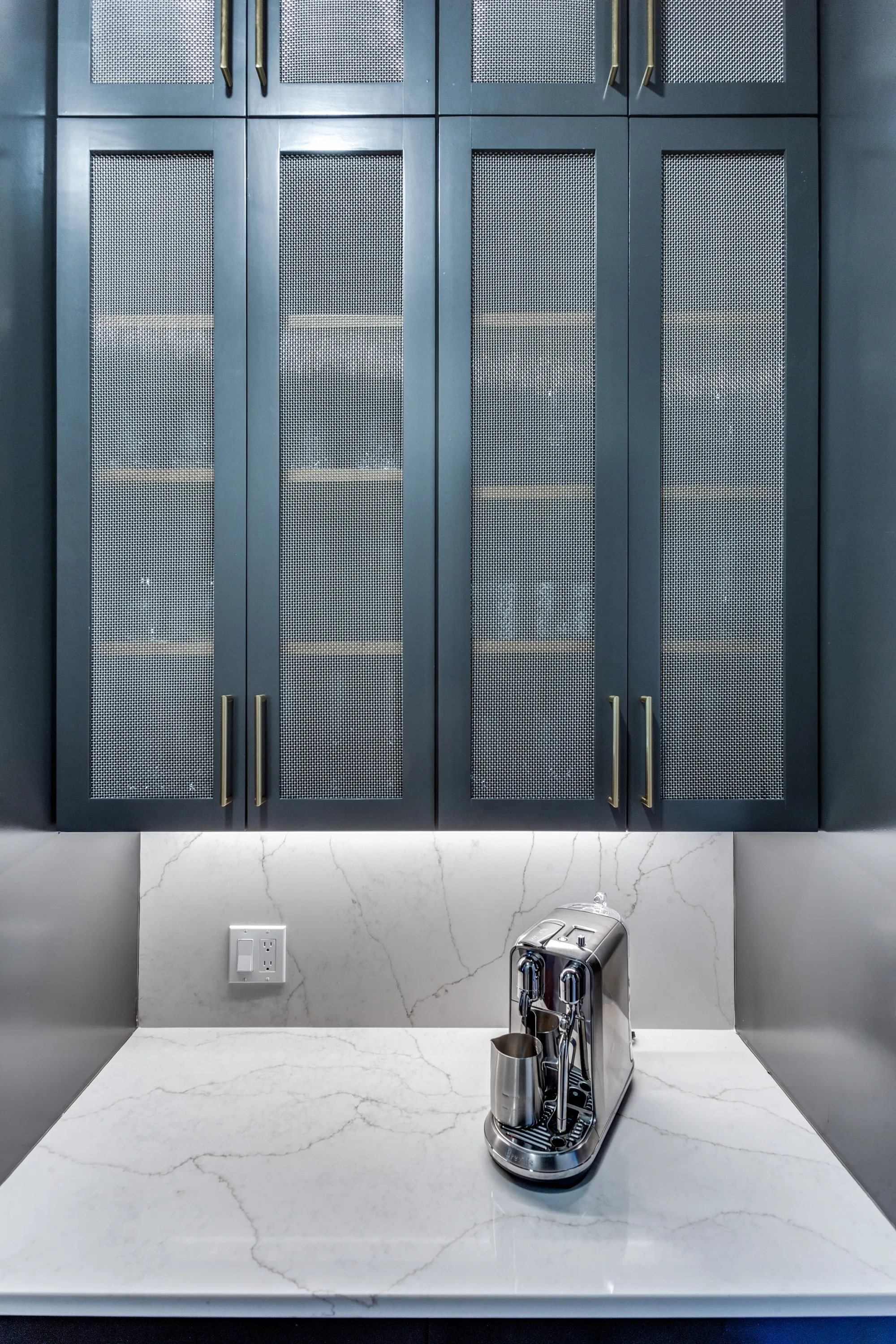 Butler's pantry coffee station with deep blue wire-mesh cabinetry and quartz counter