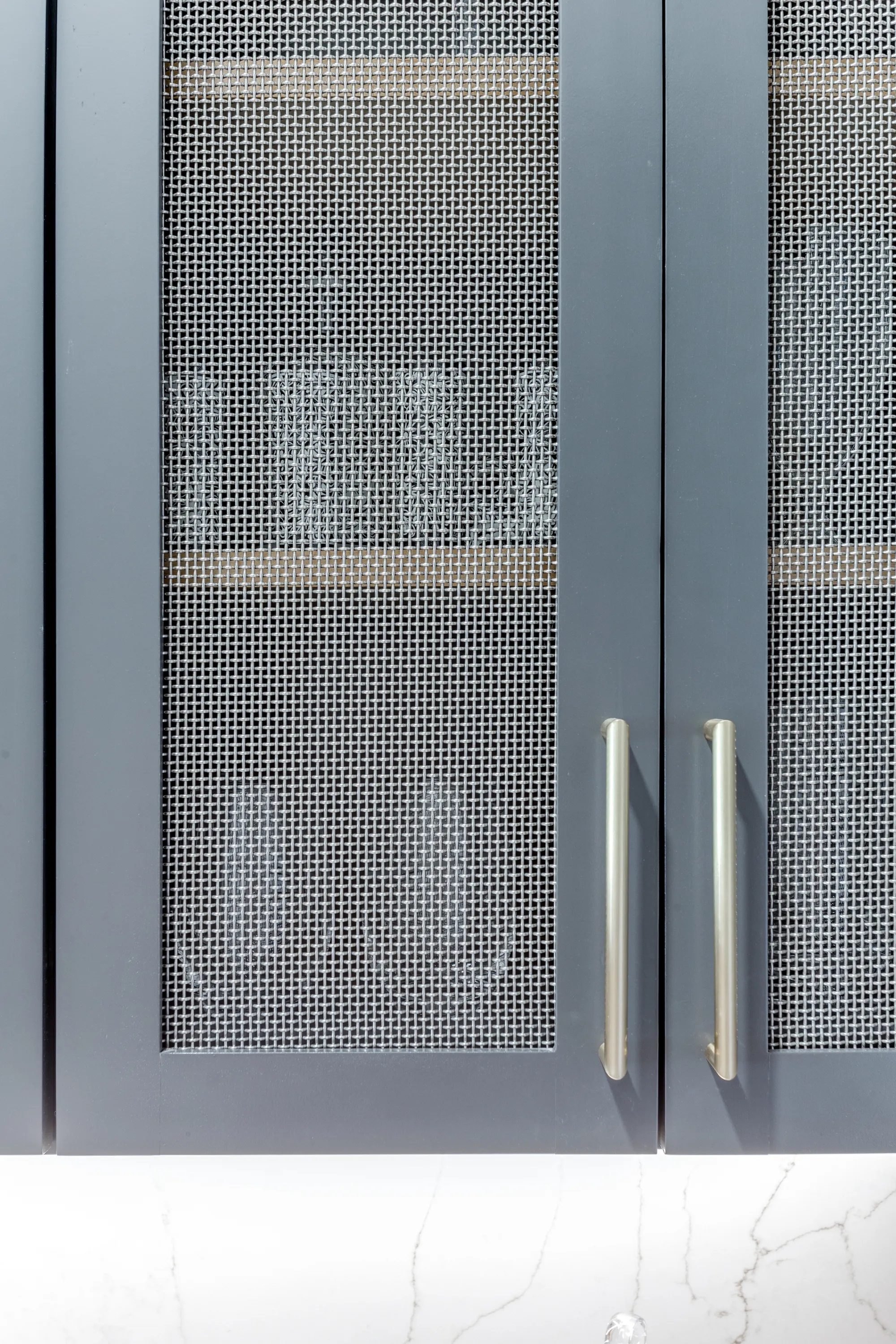 Wire-mesh cabinet door detail with brass hardware