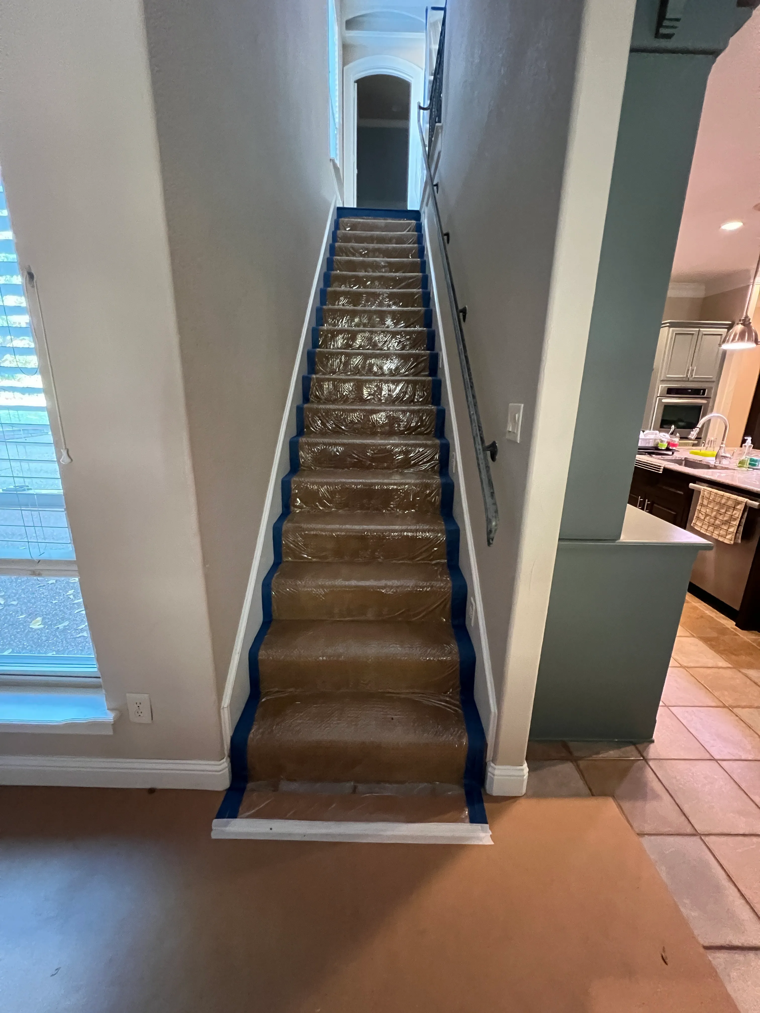 Stair treads wrapped in ram-board and taped at every edge — Swanson's standard protection while construction traffic runs upstairs.