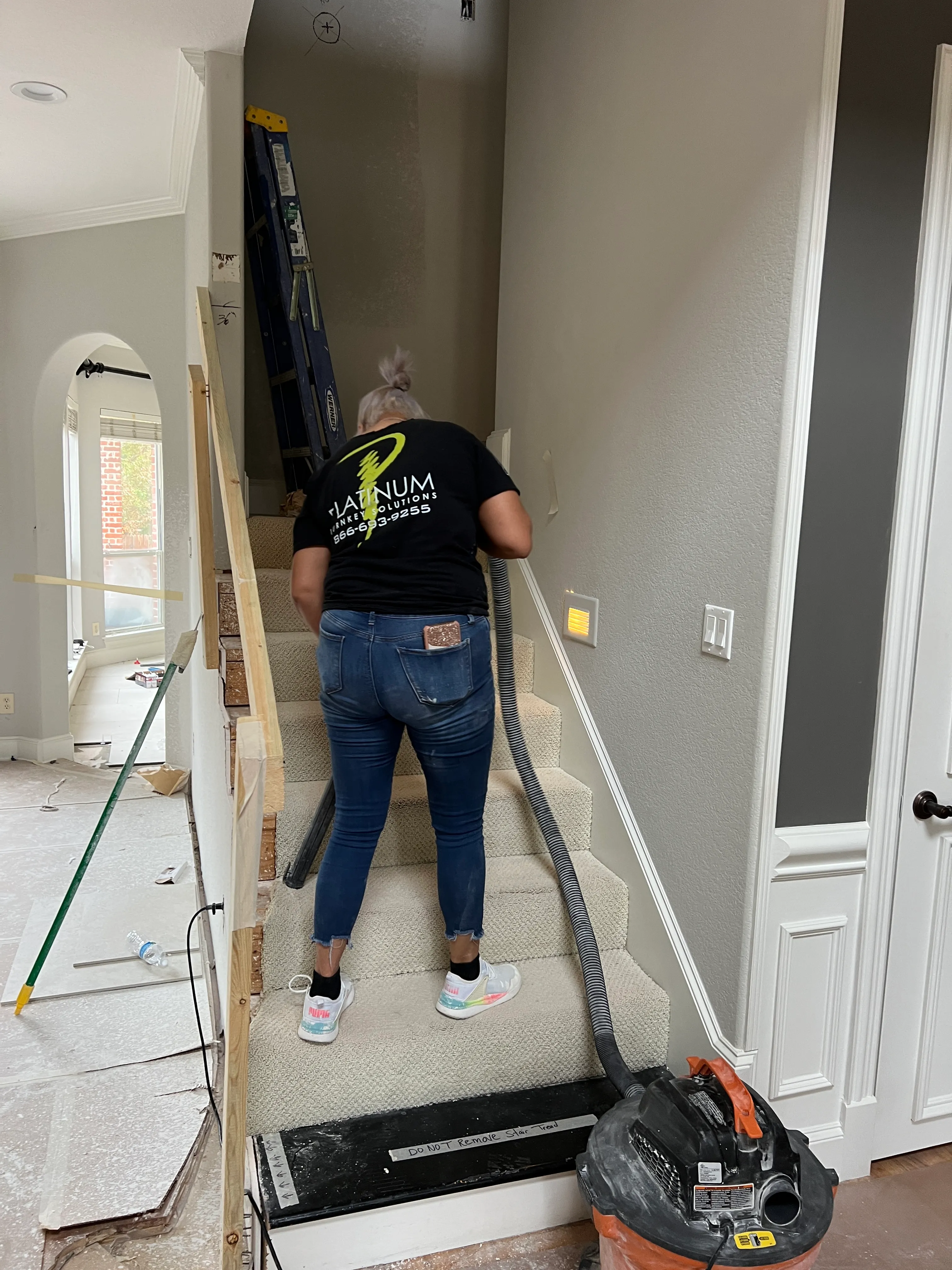 Dust-control specialist vacuuming a covered staircase mid-project.